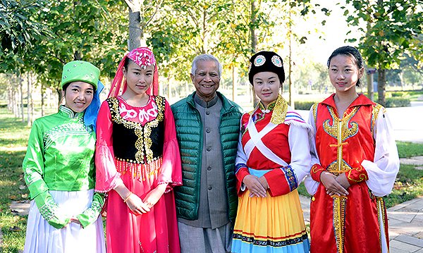 Nobel Laureate Professor Yunus flanked by Yunnan girl students of Yunnan Normal University in Kunming, China, in their traditional colorful dresses
